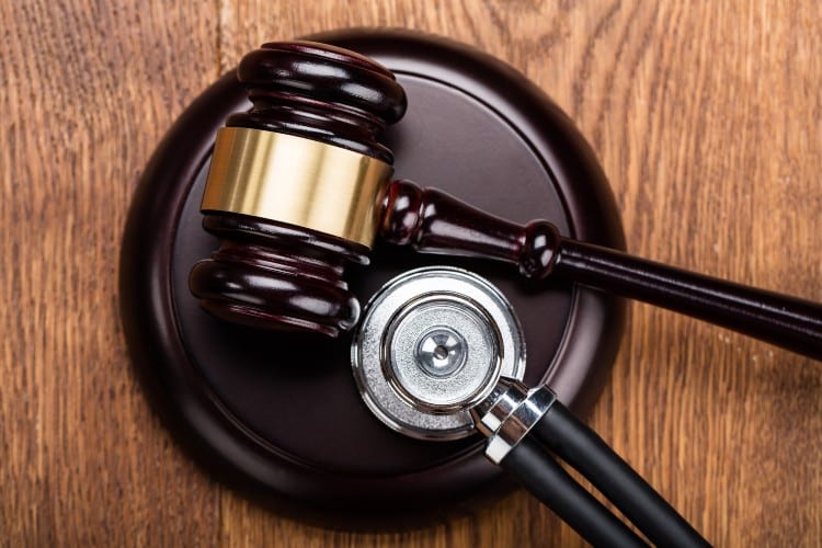 Law Judge Gavel And Medical Stethoscope On Wood Table